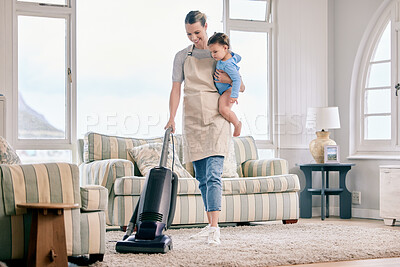 Buy stock photo Shot of a mom vacuuming the living room with her baby on her arm
