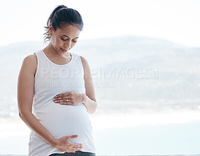 Buy stock photo Shot of a pregnant woman rubbing her belly at home
