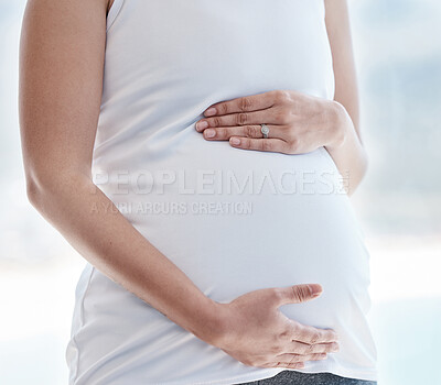 Buy stock photo Shot of a pregnant woman rubbing her belly at home