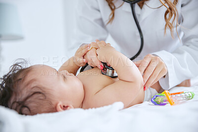 Buy stock photo Shot of a doctor listening to the heartbeat of a little baby using a stethoscope
