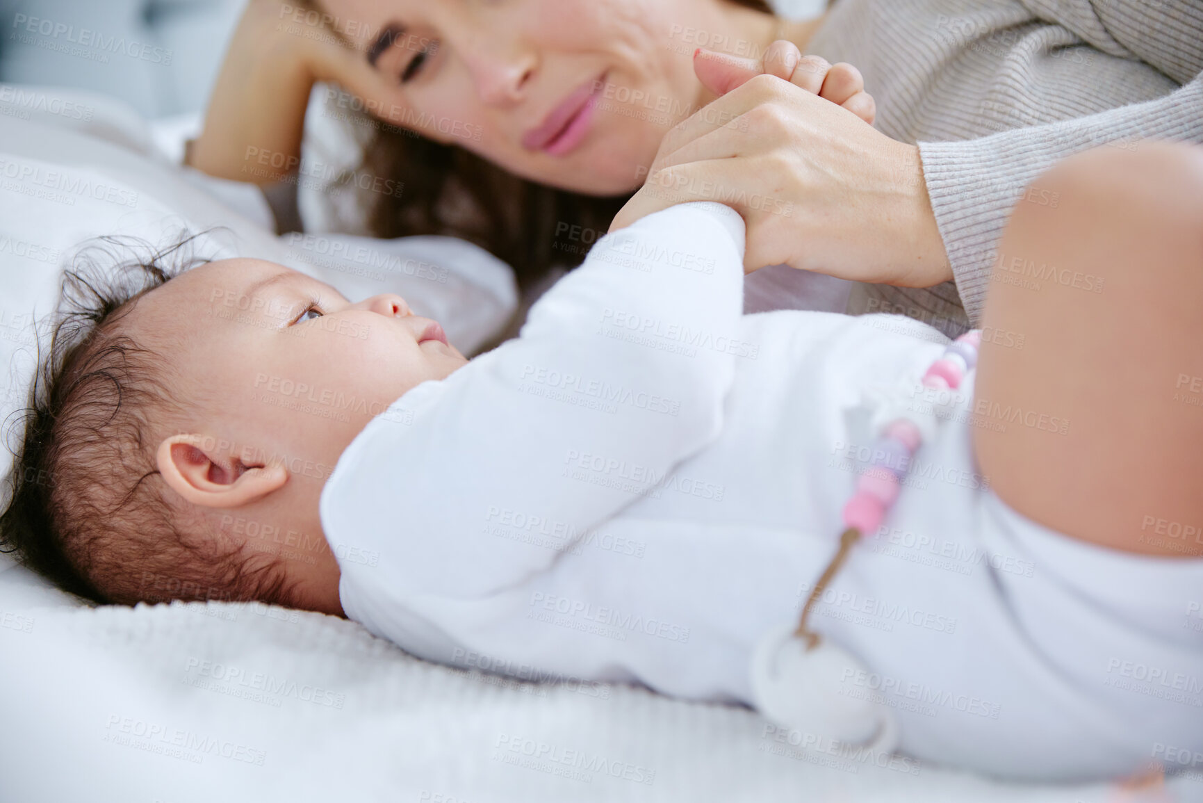 Buy stock photo Mother, baby and bed with cuddle for play time, care or support with love or embrace at home. Mom holding hands with newborn, child or little kid for youth, development or bonding in bedroom at house