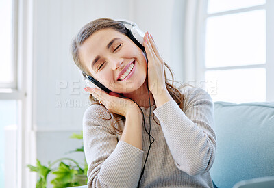 Buy stock photo Cropped shot of an attractive young woman listening to music while relaxing on the sofa at home