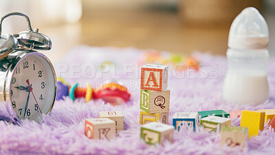 Buy stock photo Still life shot of a clock, toys and a baby bottle on a fluffy mat