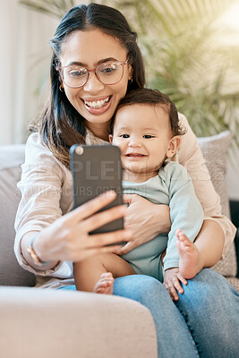 Buy stock photo Shot of a woman looking at her cellphone while sitting with her baby on her lap