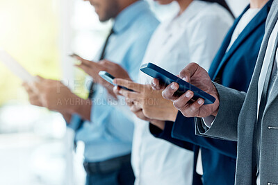 Buy stock photo Shot of a group of unrecognizable businesspeople using their devices in a modern office