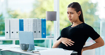 Buy stock photo Shot of a pregnant businesswoman experiencing pain while working in an office