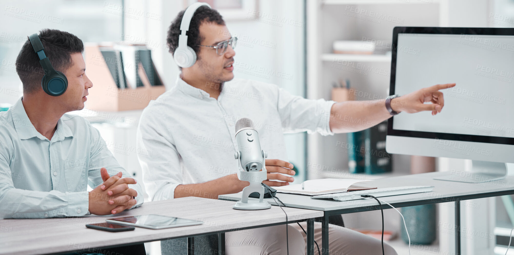 Buy stock photo Men, broadcast and pointing at screen in workplace, teamwork with technology and mockup space. Journalist, together and desk with computer for live stream or radio news, office with gear for podcast