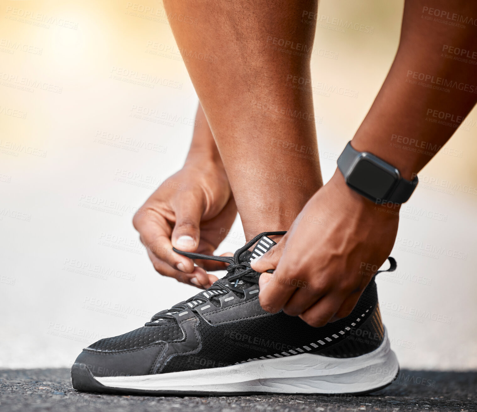 Buy stock photo Shot of a unrecognizable man tying his shoelaces outside