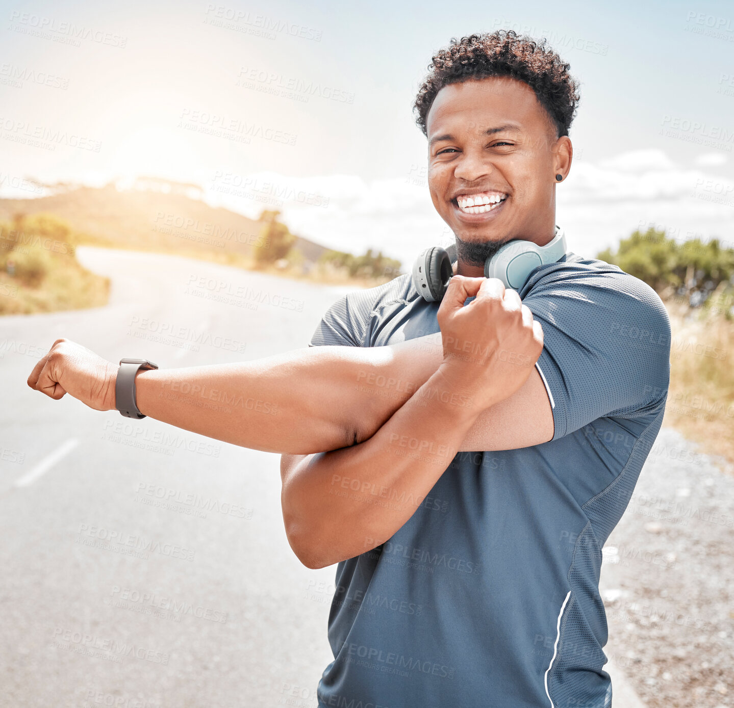 Buy stock photo Stretching arm, portrait and African man in road for morning exercise, wellness or fitness routine. Sports, smile and athlete person with headphones for running, preparing or warm up muscles