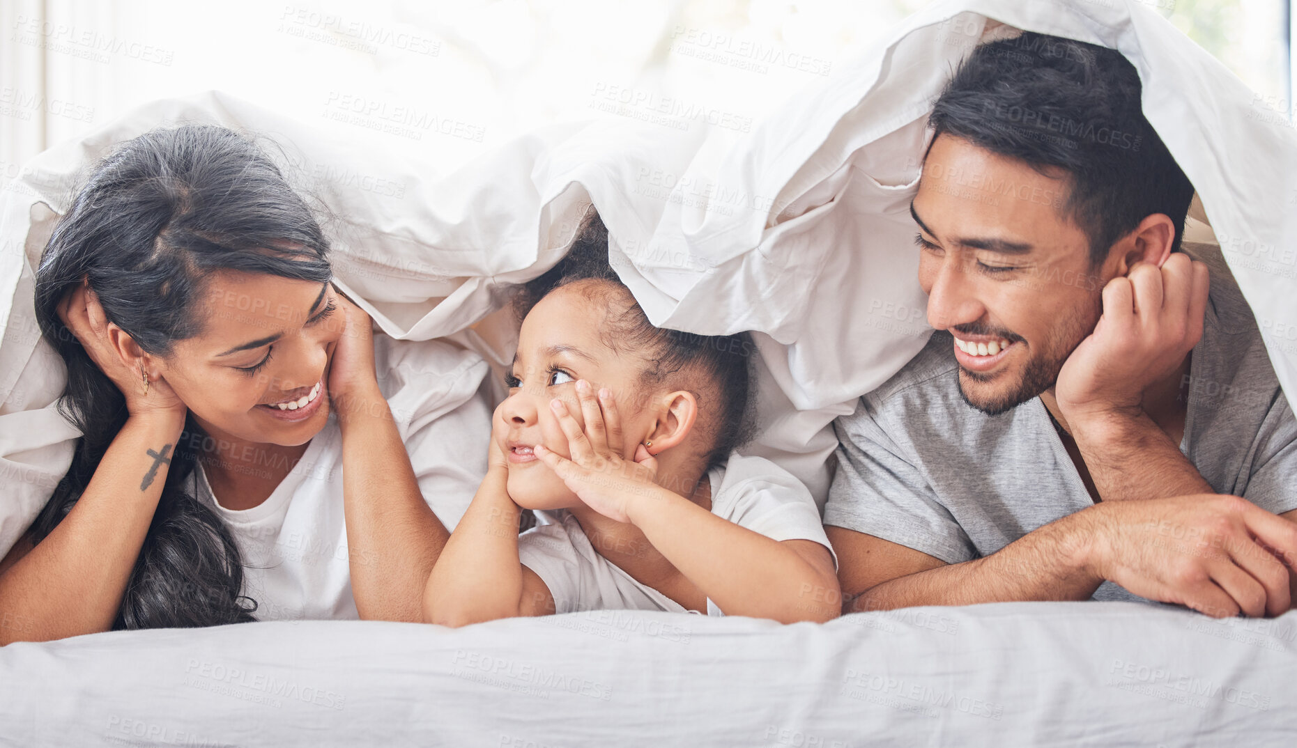 Buy stock photo Shot of a little girl lying between her mother and father on their bed