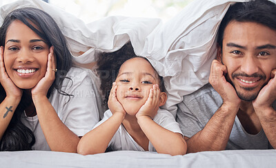 Buy stock photo Shot of a little girl lying between her mother and father on their bed
