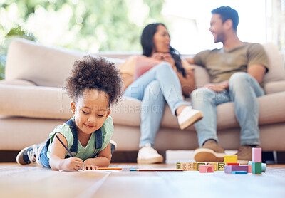 Buy stock photo Full length shot of an adorable little girl drawing while lying on the living room with her parents in the background