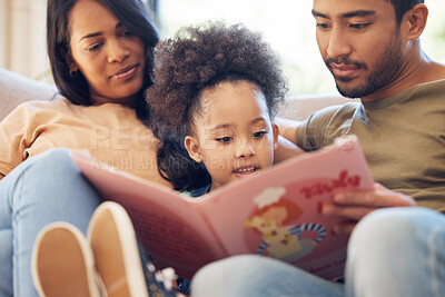 Buy stock photo Cropped shot of an affectionate young family of three reading a book while sitting in the living room at home