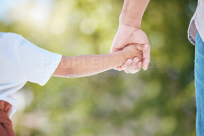 Buy stock photo Cropped shot of a little girl holding her mother's hand while walking outside