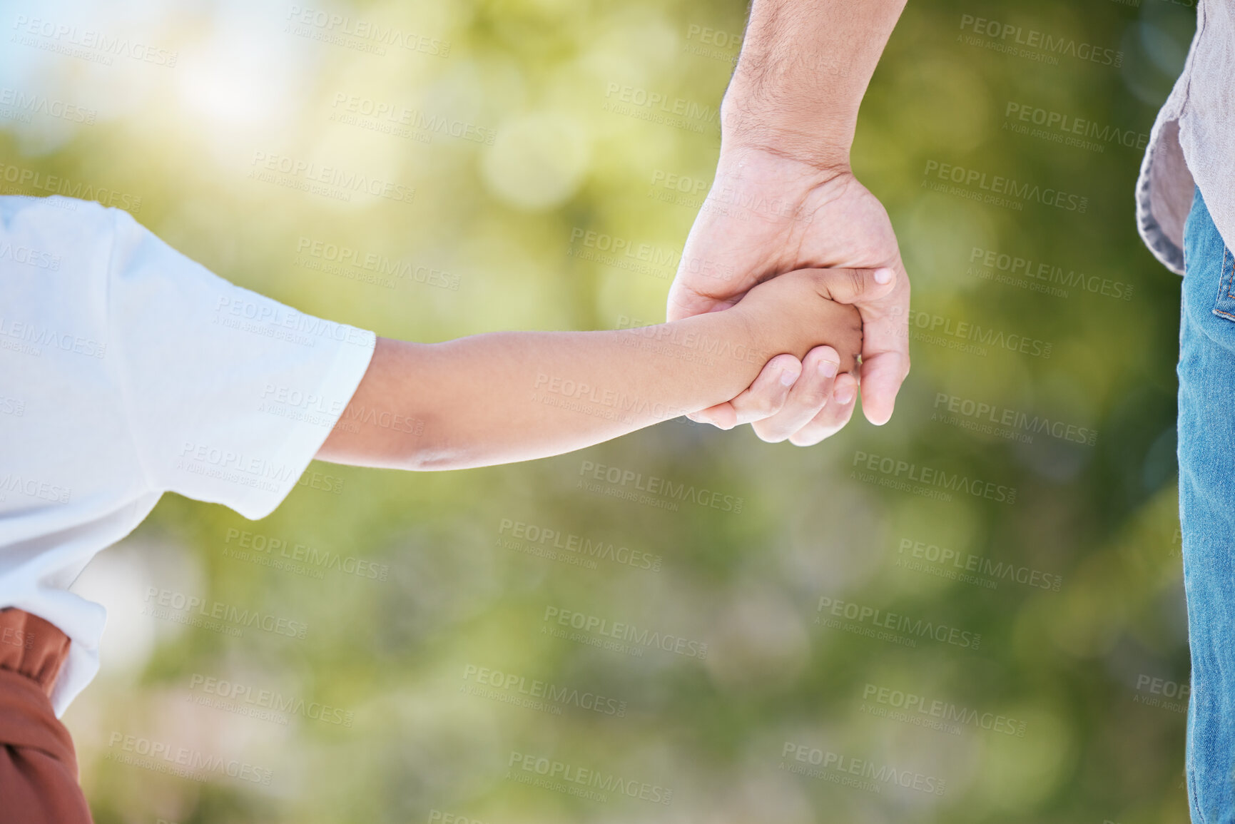 Buy stock photo Cropped shot of a little girl holding her mother's hand while walking outside