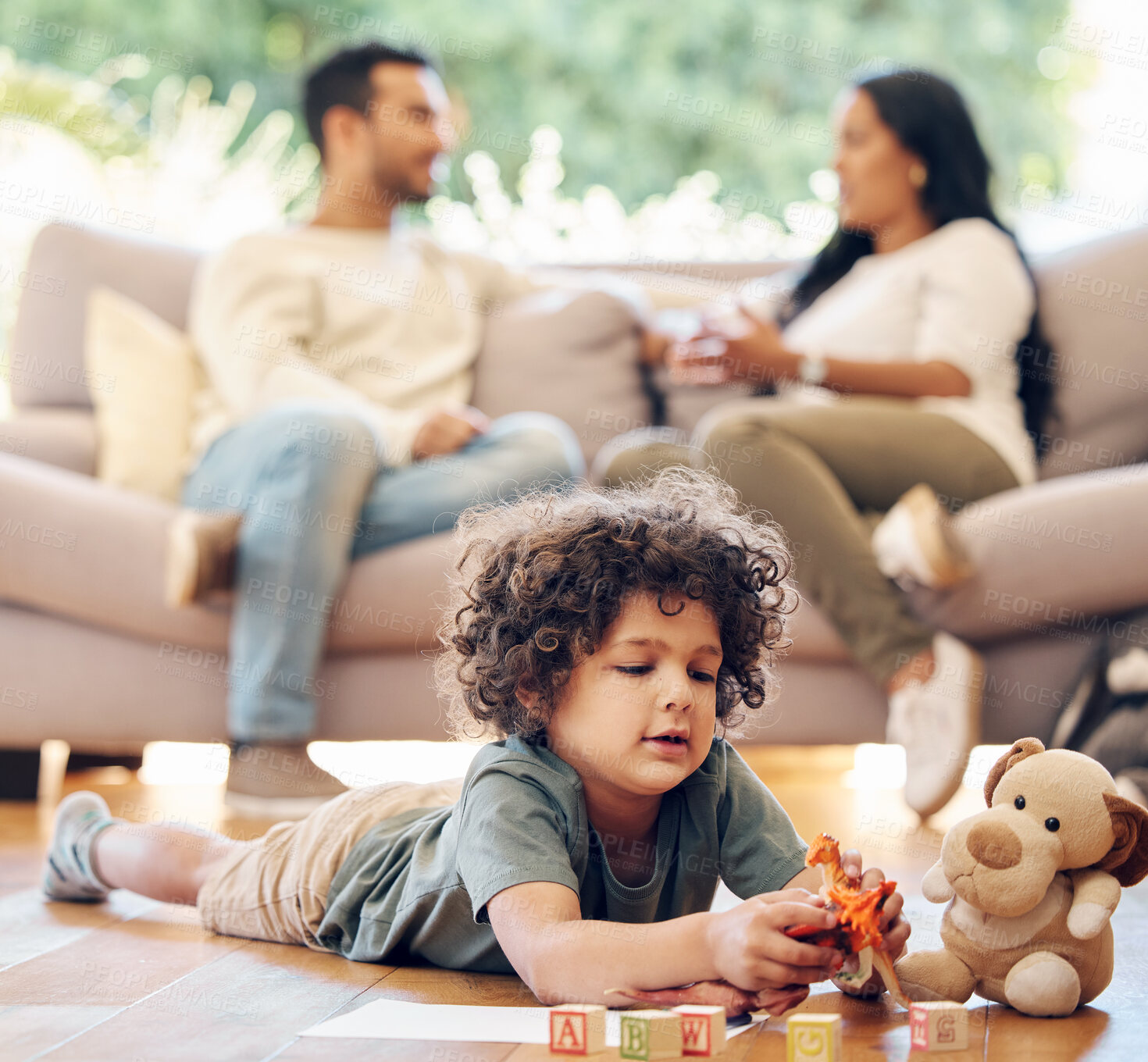 Buy stock photo Shot of a little boy playing with his toys while his parents sit in the background