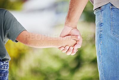 Buy stock photo Closeup shot of a little boy holding his father's hand while walking together outdoors