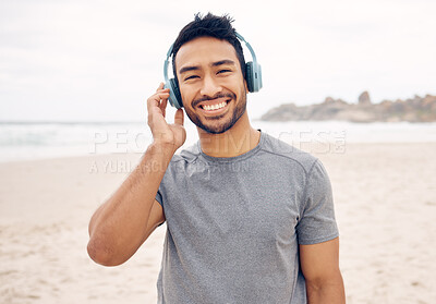 Buy stock photo Portrait of a sporty young man wearing headphones while exercising on the beach