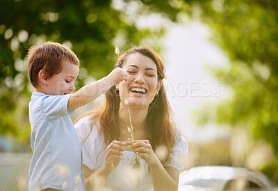 Buy stock photo Shot of a young mother and son picking flowers in nature
