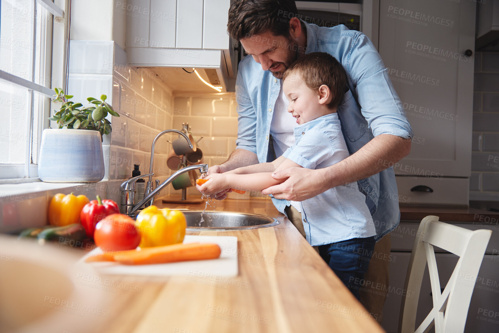 Buy stock photo Shot of a young boy and his father rinsing vegetables at home