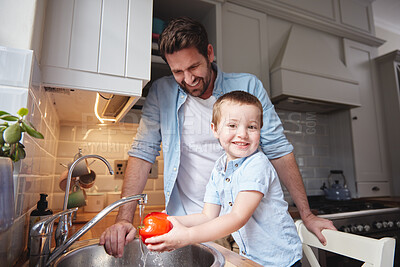 Buy stock photo Shot of a young boy and his father rinsing vegetables at home