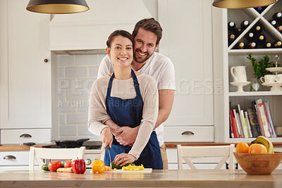 Buy stock photo Shot of a man embracing his wife while she prepares a meal in the kitchen