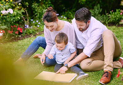 Buy stock photo Shot of a family reading a book outside