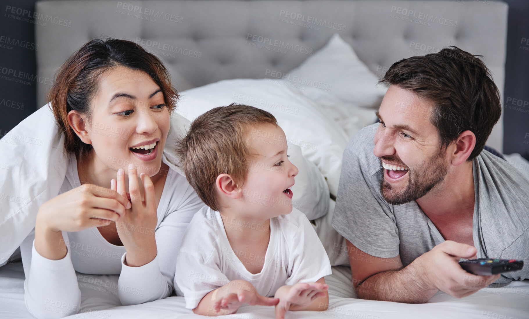 Buy stock photo Smile, son and family in bedroom, remote and bonding with love, man and woman with movies for boy in home. Mom, dad and kid together on bed, happiness and watch to relax, parents and child in house