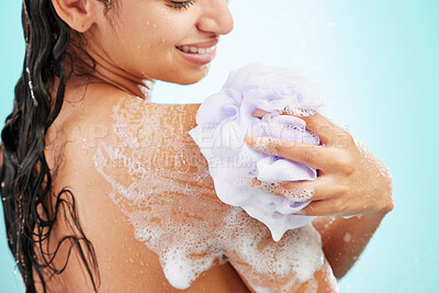 Buy stock photo Shot of an young woman enjoying a soapy shower against a blue background