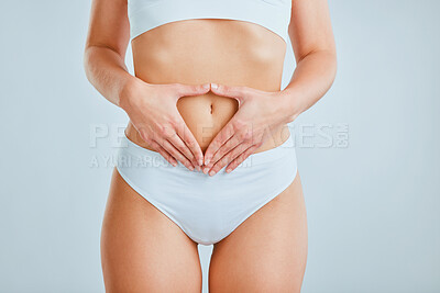 Buy stock photo Cropped shot of a woman holding her hands over her stomach