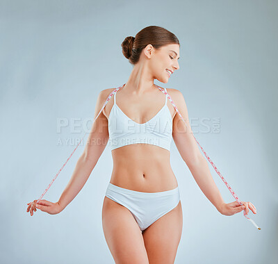 Buy stock photo Shot of a woman posing with a measuring tape against a grey background