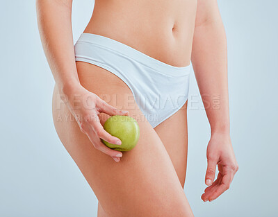 Buy stock photo Cropped shot of an unrecognizable woman holding an apple against her thigh