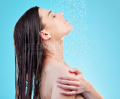 Buy stock photo Shot of a beautiful young woman enjoying a refreshing shower against a blue background