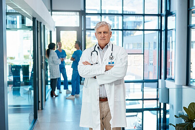 Buy stock photo Shot of a mature male doctor standing with his arms crossed at a modern hospital