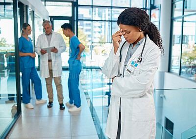 Buy stock photo Shot of a young female doctor suffering from a headache at a modern hospital