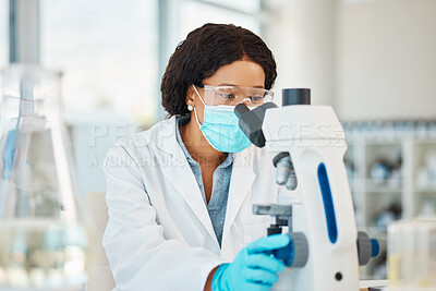 Buy stock photo Shot of a young scientist using a microscope in a lab