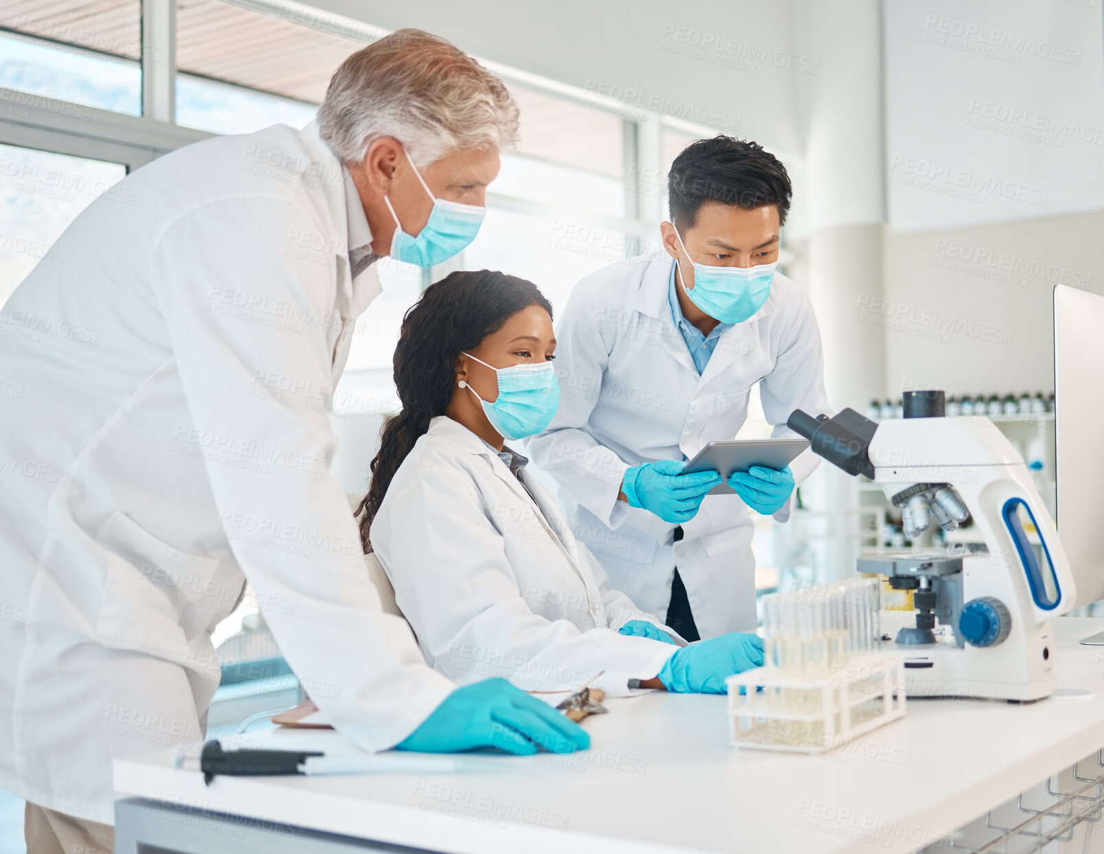 Buy stock photo Shot of a group of scientists working together on a computer in a lab