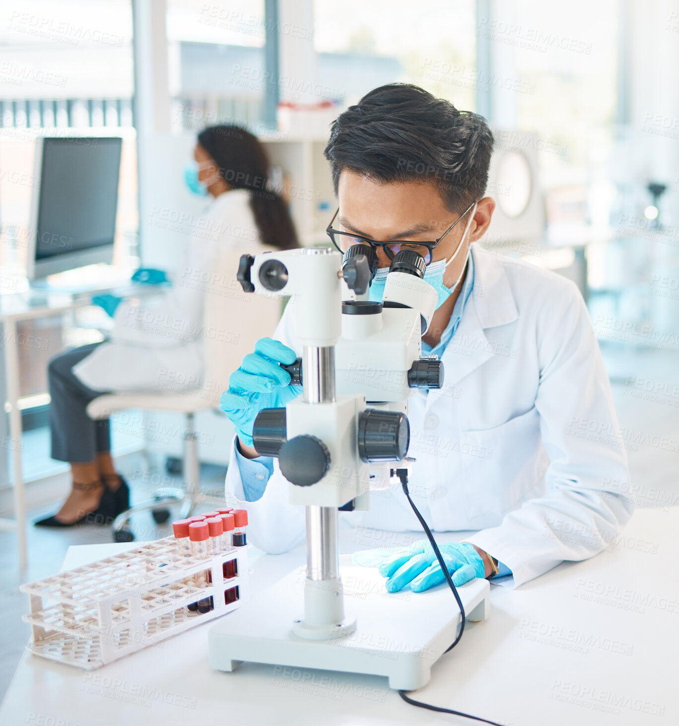 Buy stock photo Shot of a young scientist using a microscope in a lab