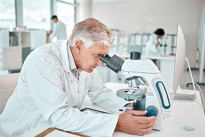 Buy stock photo Shot of a senior scientist using a microscope in a lab
