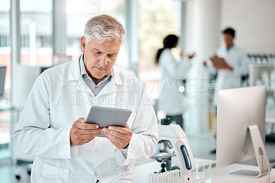 Buy stock photo Shot of a senior scientist using a digital tablet in a lab