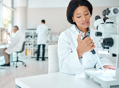Buy stock photo Shot of a young scientist working with samples while using a microscope in a lab