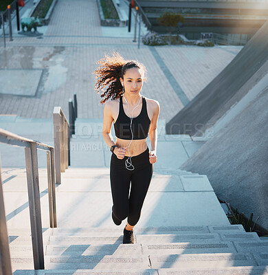 Buy stock photo Woman, earphones and running up stairs in city, outdoor fitness and music for workout motivation. Female person, steps and listening to song or audio in town for training, exercise and cardio action