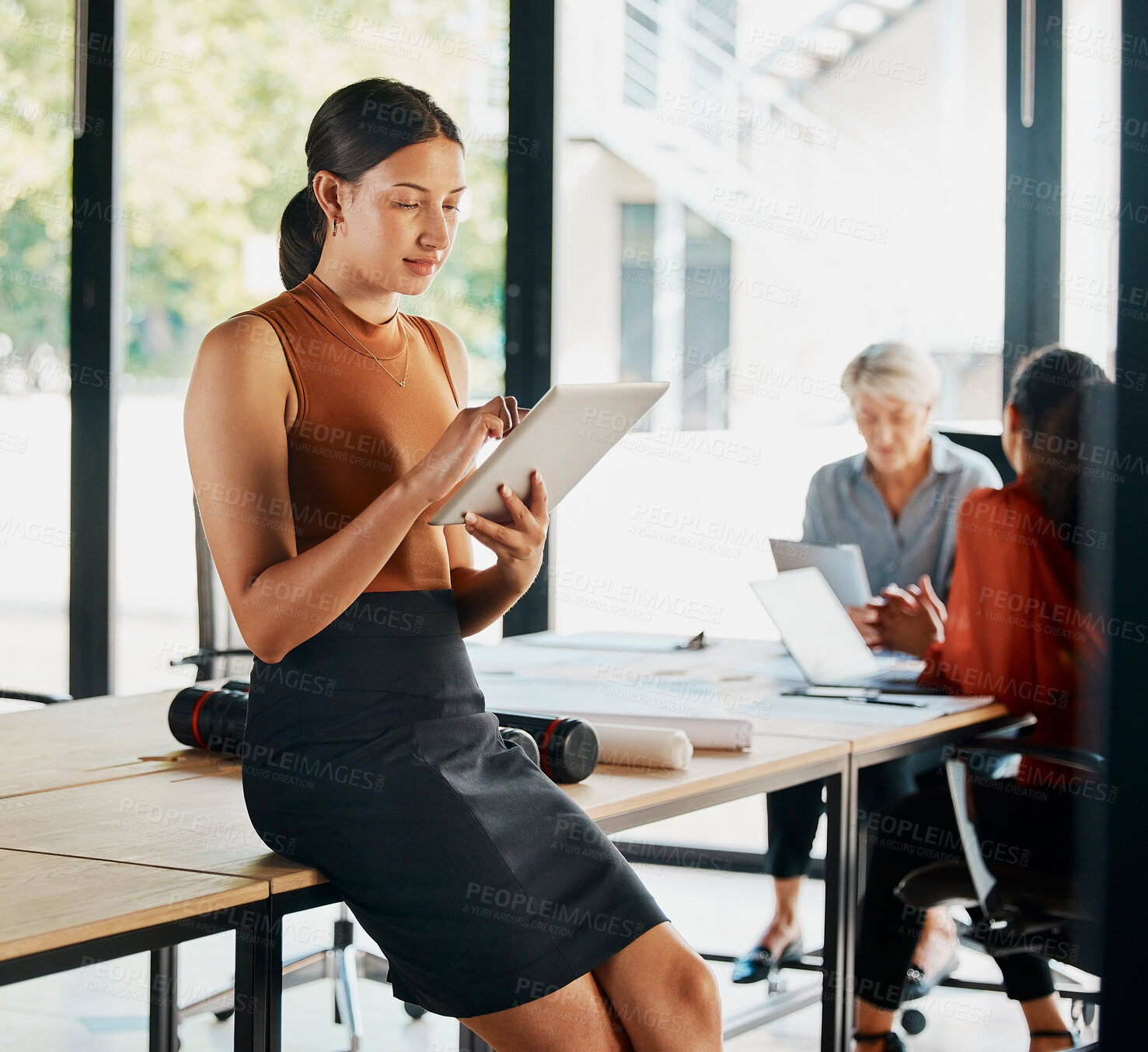 Buy stock photo Cropped shot of an attractive young businesswoman using her tablet while standing in the boardroom