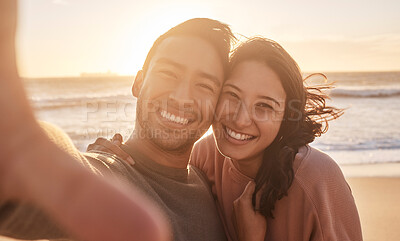 Buy stock photo Portrait of a young diverse biracial couple taking a selfie at the beach and having fun outside