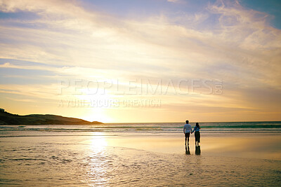 Buy stock photo Rearview shot of an unrecongnizable couple enjoying a romantic walk at the beach