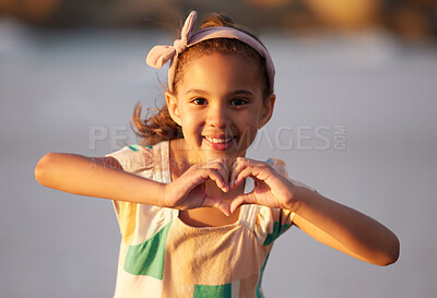 Buy stock photo Shot of an adorable little girrl showing a heart shale with her fingers at the beach