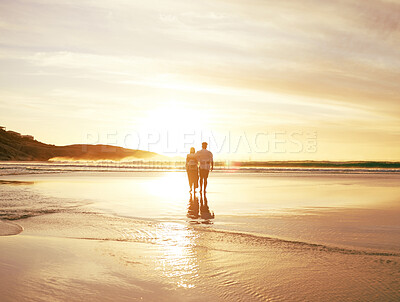 Buy stock photo Rearview shot of an unrecongnizable couple enjoying a romantic walk at the beach