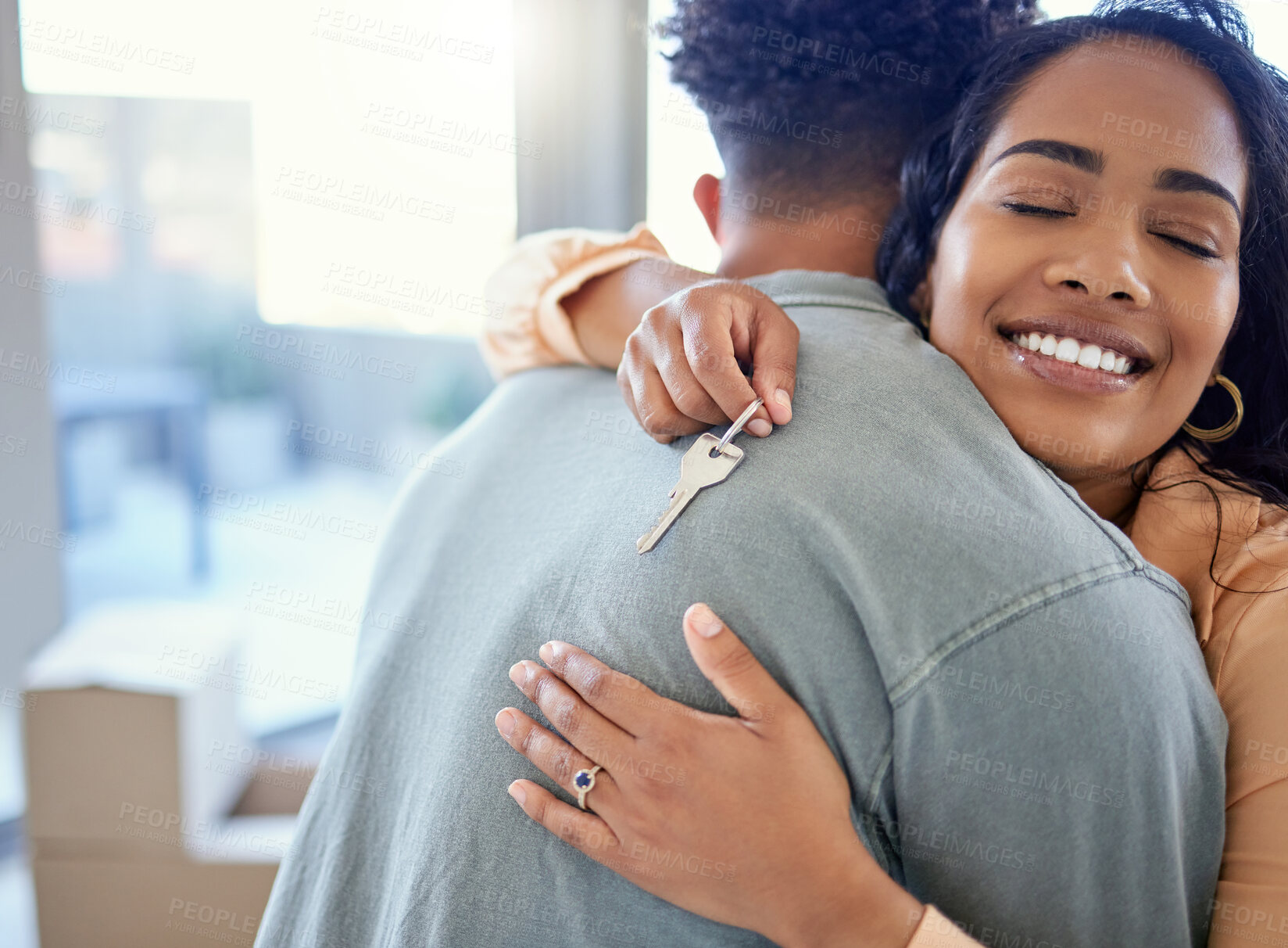 Buy stock photo Happy couple, hug and real estate with key for moving in new home or mortgage loan together indoors. Woman hugging man with smile in happiness, property or investment with keys to apartment building