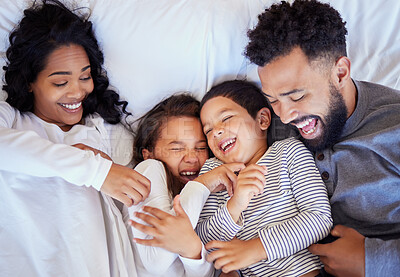 Buy stock photo Happy family, playing and laughing with children above on bed for fun morning, tickle or wake up at home. Top view of playful father, mother and kids lying with smile in bedroom for bonding at house