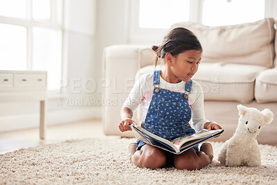 Buy stock photo Shot of an adorable little girl reading to her teddy while sitting on the floor at home